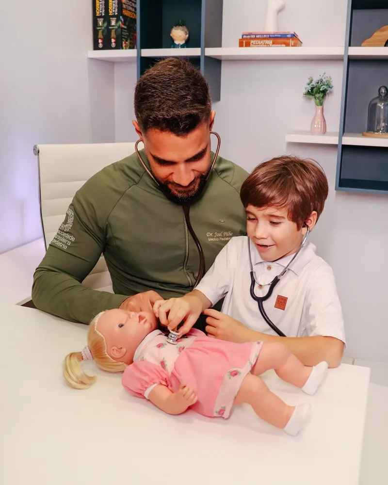 Pediatra e criança usando um estetoscópio em uma boneca